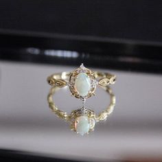 an opal and diamond ring is displayed in front of a mirror