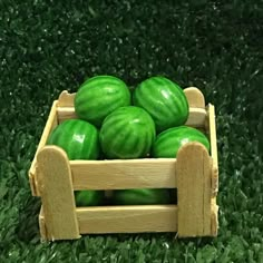 a wooden crate filled with green watermelons on top of grass