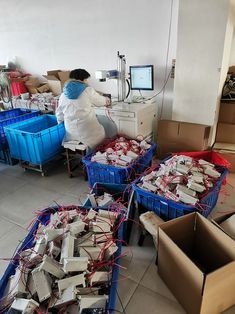 a woman in white lab coat standing next to boxes filled with electronic equipment and wires