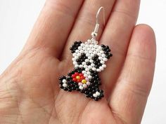 a hand holding a small black and white beaded dog