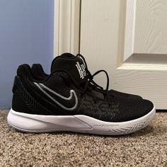 a pair of black and white shoes sitting on top of a carpeted floor next to a door