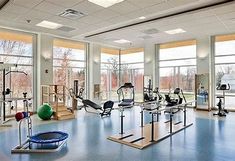 a gym with exercise equipment and large windows