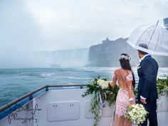 a bride and groom standing on the deck of a boat in front of niagara falls