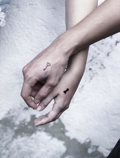 two people holding hands with tattoos on their fingers