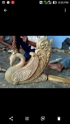 some people are working on a sculpture in the process of being carved with woodworking tools