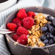 a bowl filled with granola, raspberries and blueberries