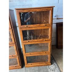 an old wooden bookcase with glass doors on the front and bottom shelves, next to a rug