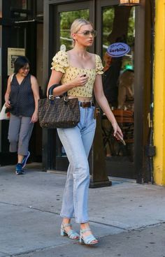 a woman walking down the street carrying a brown purse