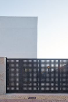 a tall white building sitting next to a metal fence