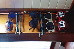 several pairs of sunglasses sitting on top of a wooden shelf with the word love spelled out