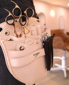 a person holding a pink leather purse with scissors in it and two pairs of shears sticking out of the pocket