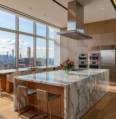 a kitchen with marble counter tops and an island in front of large windows overlooking the city