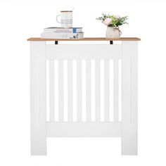 a white wooden table with some books on top and a vase filled with flowers next to it