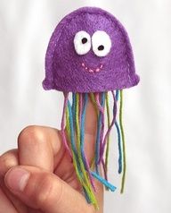 a hand holding up a purple jellyfish with eyes and long hair, it's made from felt