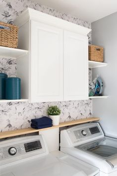 a washer and dryer in a white laundry room with wallpapered walls