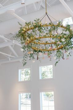 a chandelier hanging from the ceiling in a white room with two large windows