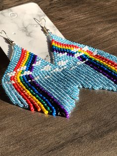 a pair of colorful beaded earrings sitting on top of a wooden table