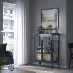 a living room with a blue cabinet in the corner and a painting on the wall