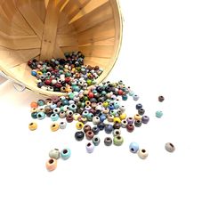 a wooden bucket filled with lots of beads on top of a white table next to a pair of scissors