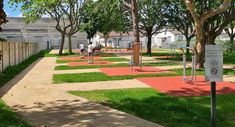 an empty park with trees and grass on both sides, people walking down the path