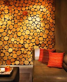 a living room filled with furniture and lots of tree trunks on the wall behind it