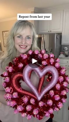 a woman holding a heart shaped wreath with pink roses in the shape of two hearts