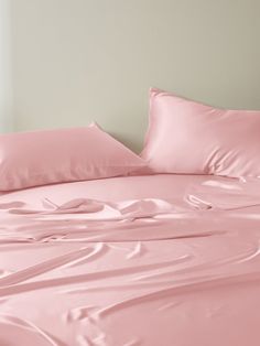 a bed with pink sheets and pillows on it