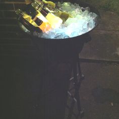 an ice bucket filled with bottles of wine sitting on top of a sidewalk next to a street