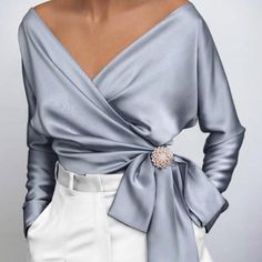 This 1940s top is at the height of Hollywood glam. Wide V-neck to envelop your cleavage and wrap subtly around the waist, creating the illusion of a beautifully draped torso. 

The satiny, stretchy fabric shines and makes this top a must-have for parties and evenings. Add a rhinestone brooch to elevate the top and pair it with one of our high waisted pencil skirts. 
Material: Polyester, Spandex
Details: V-neck wrap top, Bow at the waist, Long sleeves, Available in Plus Size, Brooch not included! Satin T Shirt, Rock Outfit, Retro Mode, Women Tunic Tops, Satin Shirt, Satin Blouse, Moda Vintage, Satin Top, Elegant Shirt