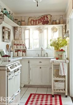 a white kitchen with red and white checkered rugs on the floor next to an oven