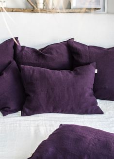 purple pillows are stacked on top of each other