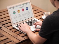 a person sitting at a table with a laptop on their lap and coffee in front of them