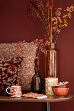 a table topped with vases filled with flowers next to pillows and pillow cases on top of a wooden table