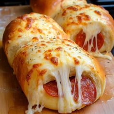 two pepperoni and cheese pizza rolls on a cutting board