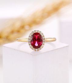 a close up of a ring with a red stone in it on a white box