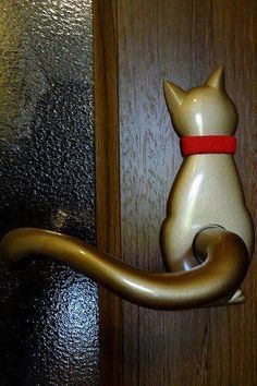 a door handle with a cat figurine sitting on it's back end