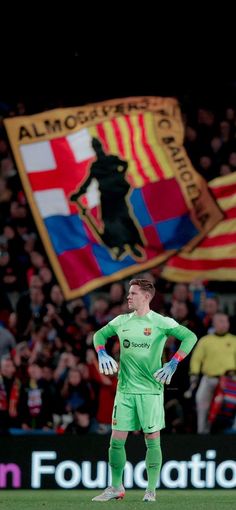 a man standing on top of a soccer field in front of a flag and banner