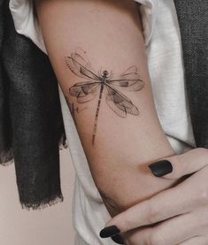 a woman's arm with a dragonfly tattoo on it