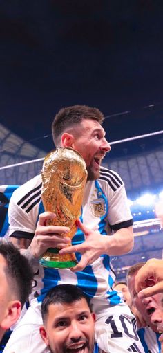 a soccer player is holding the trophy in front of his head while other players look on