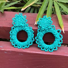 two pairs of turquoise beaded earrings sitting on top of a wooden bench