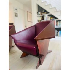 a purple chair sitting on top of a hard wood floor next to a stair case