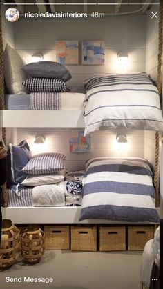 three shelves with pillows and blankets on them in a room that has lights above the beds