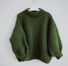 a green sweater hanging on a white hanger