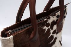 This brown and white cowhide tote purse combines rustic charm with urban sophistication, making it a unique accessory for everyday use. - Free shipping on all cowhide tote purses - Dimensions: 16" Length x 12" Height x 4" Wide - Capacity to comfortably fit a laptop, tablet, phone, wallet, charger, and other essentials - Features of the tote/handbag: - Lined interior - Zipper pockets inside - Made from high-quality cowhide leather - Double-stitched seams for durability - Thick stitching details - Production time: Approximately seven business days per purse - Note: The cowhide bag received will be similar to the one in the picture but not identical, as each cowhide is unique A cowhide tote purse in striking dark brown and white is not just an accessory; it's a statement piece that embodies t Metallic Cowhide Rug, Thick Stitching, Cowhide Purse, Urban Sophistication, Leather Waist Bag, Real Leather Bags, Cowhide Bag, Brown Cowhide, Leather Apron