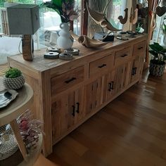 a large wooden dresser sitting inside of a living room next to a wall mounted mirror