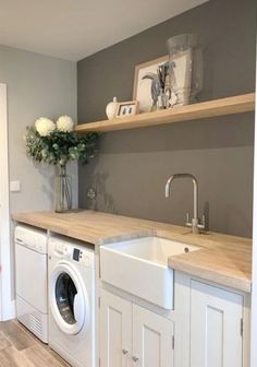 a washer and dryer in a room with wooden shelves on the wall above it