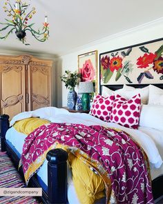 a bed with colorful pillows and blankets on top of it next to a dresser in a bedroom