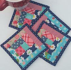 four patchwork coasters on a table with a cup of coffee in the middle