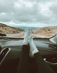 someone is sitting in the driver's seat of a car with their feet on the dashboard