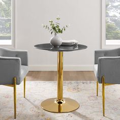 two chairs and a table with a vase on it in front of a white wall